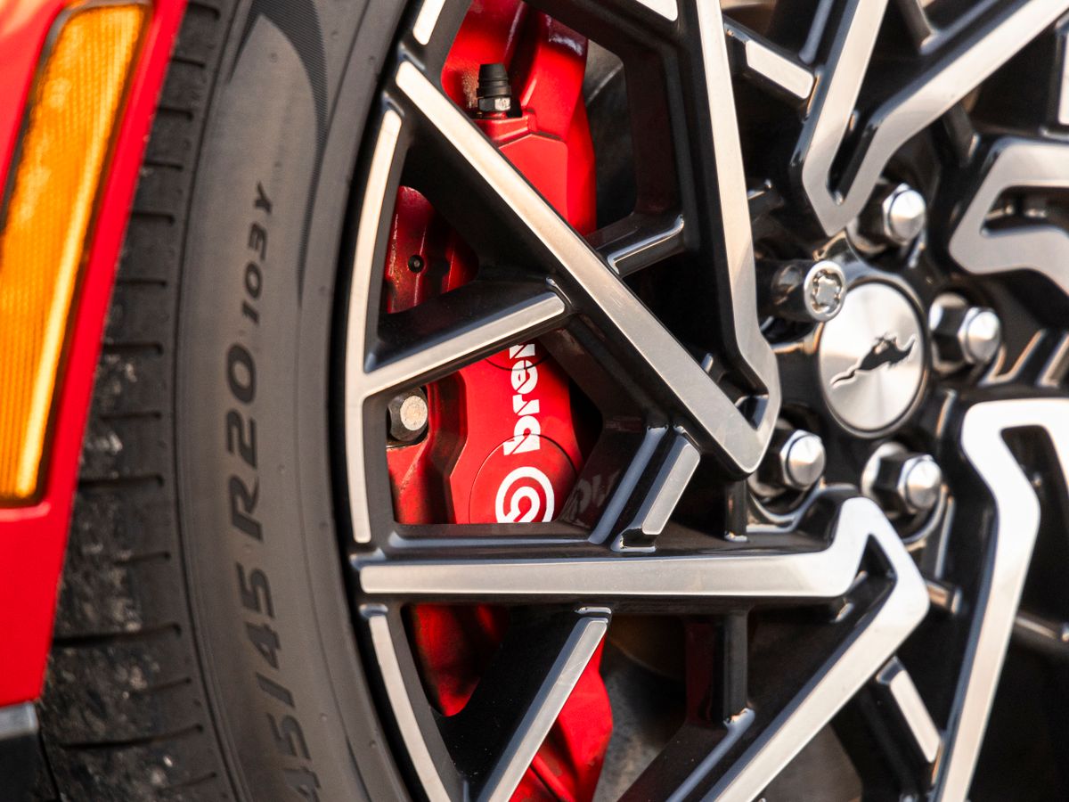 Red Brembo brake caliper behind the alloy wheel of a red sports car